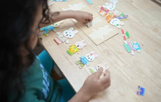 Child practicing structured play and problem-solving skills using educational puzzles during an autism-focused learning activity at OrbRom Center