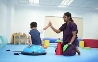 Occupational therapist supporting a child with balance and core stability activity during a pediatric session at OrbRom Center