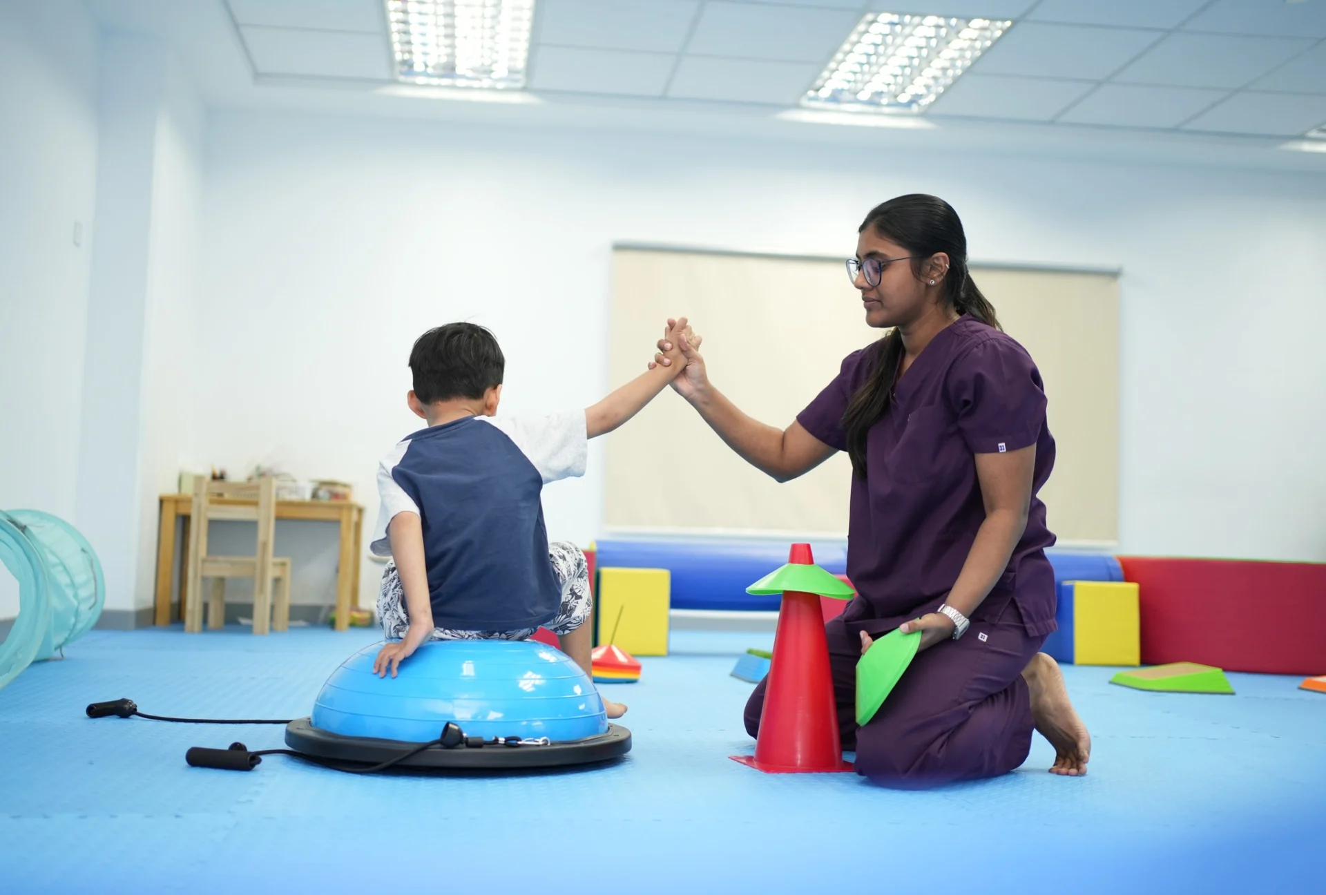 Occupational therapist supporting a child with balance and core stability activity during a pediatric session at OrbRom Center