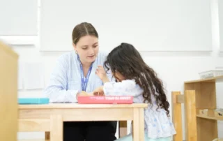 Preschool teacher supporting children during a structured classroom activity at OrbRom Center