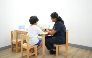 Speech therapist guiding a child through a language activity using a book during a structured therapy session at OrbRom Center