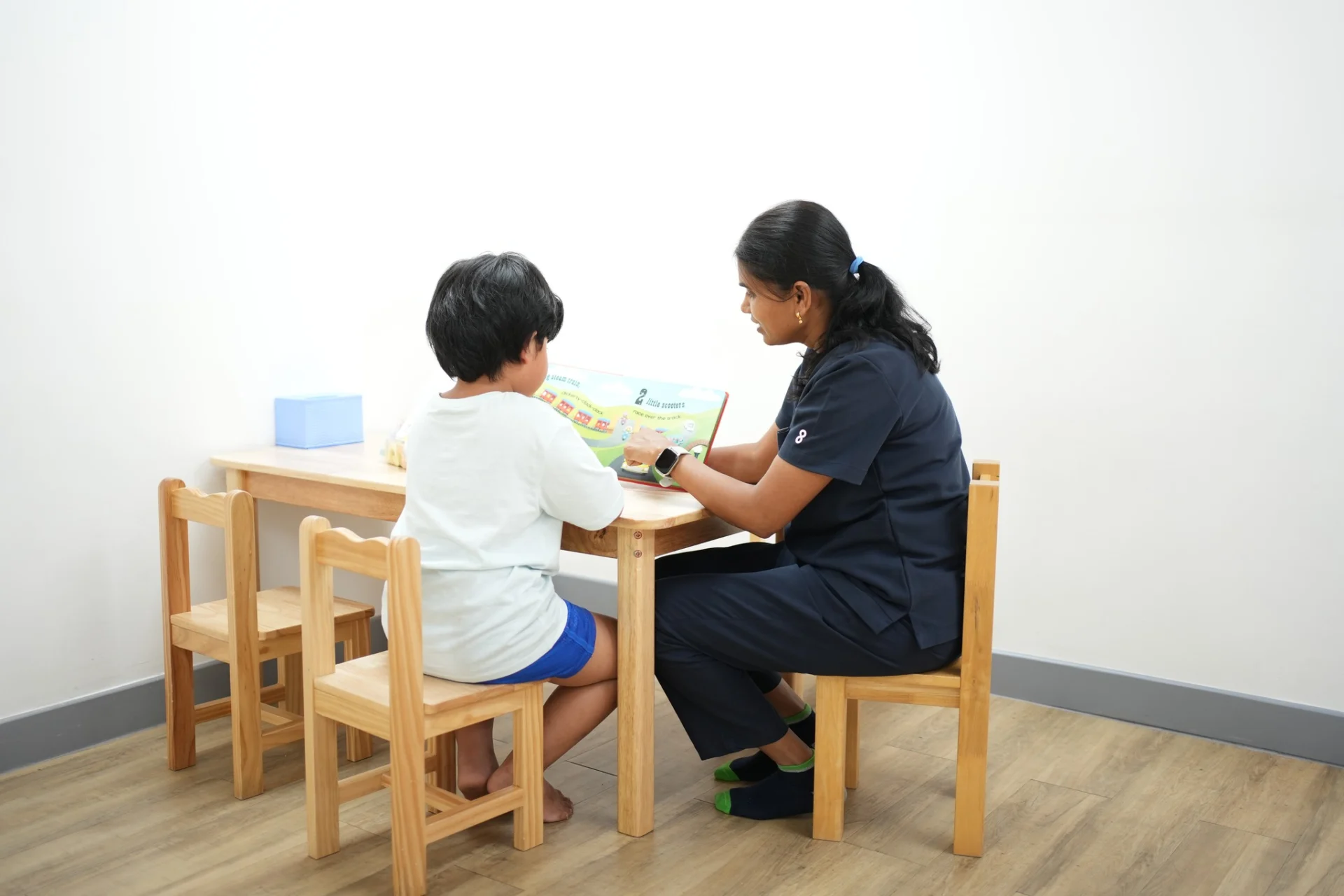 Speech therapist guiding a child through a language activity using a book during a structured therapy session at OrbRom Center