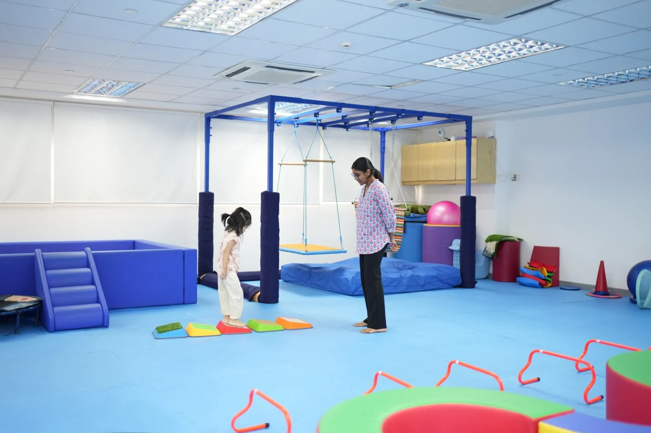 Child practicing balance and coordination activities with an occupational therapist in a sensory gym at OrbRom Center