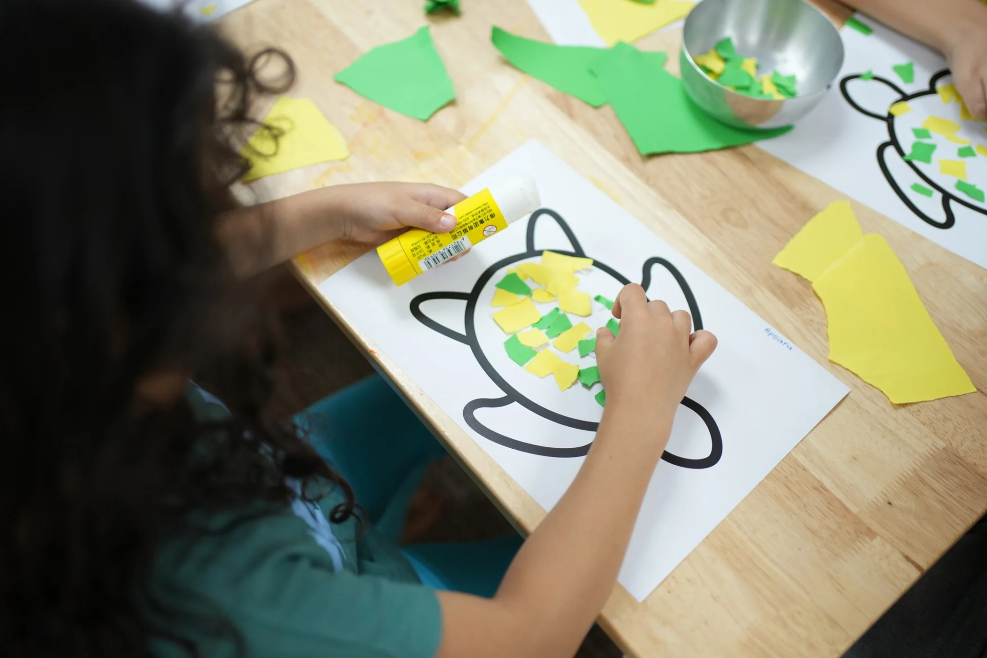 Child engaging in a cutting and pasting activity to develop coordination and focus