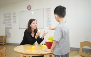 Lead teacher supporting a child during a structured learning activity at OrbRom Center