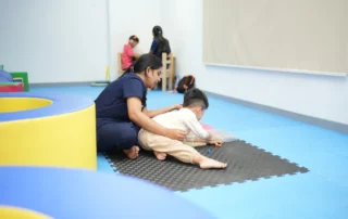 Occupational therapist supporting a child during floor-based fine motor and sensory activities.