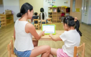 Speech therapist and child using an AAC communication tablet during an individualized speech and language therapy session at OrbRom Center.