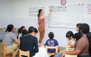 Kate encourages a student to answer a question while classmates watch attentively, promoting confidence and classroom participation.