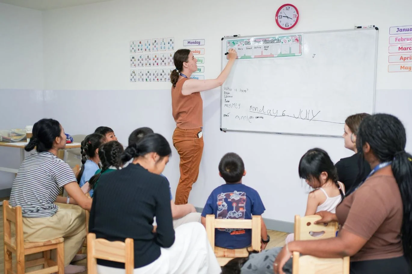 Kate encourages a student to answer a question while classmates watch attentively, promoting confidence and classroom participation.